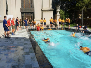 A large group of midshipmen performing fitness training in a large swimming pool