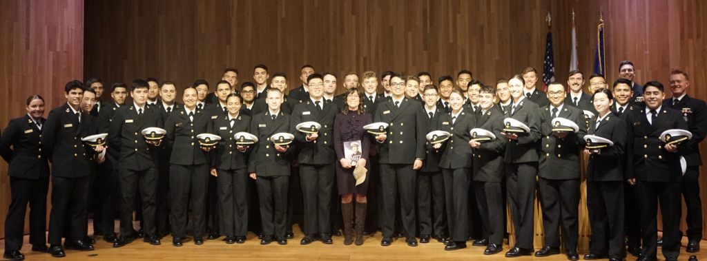 Nimitz Lecturer taking group photo with midshipmen in front of an audience