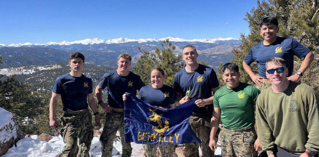 Group of six midshipmen NROTC Executive Officer holding a UC Berkeley unit flag on a snowy mountain.