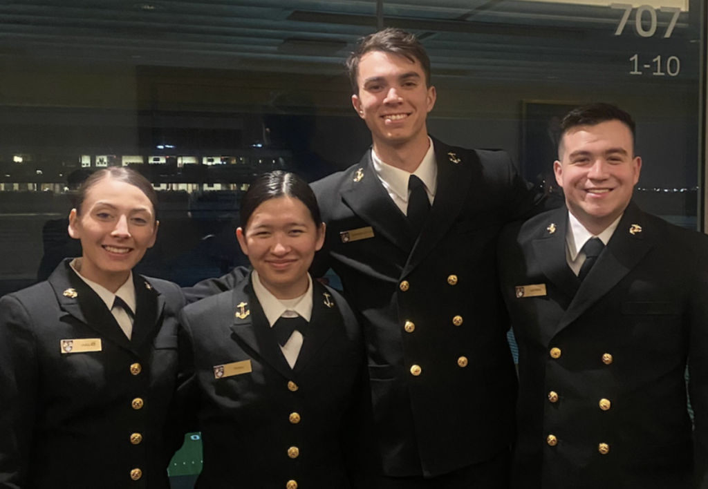 Group of four midshipmen attending the Notre Dame Naval Leadership Weekend Event wearing service dress blues uniforms
