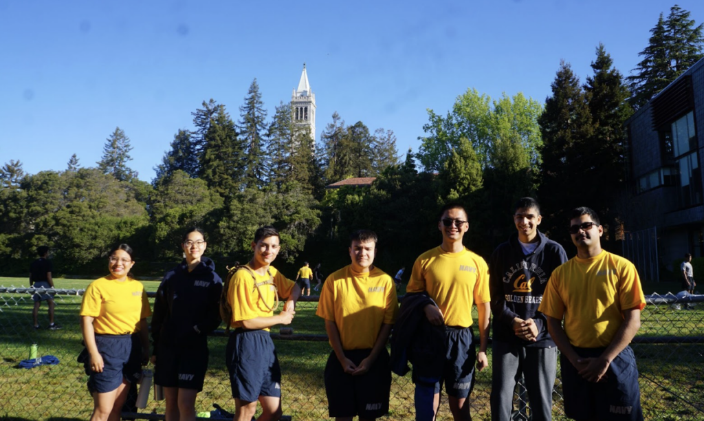 Seven midshipmen in golden bears in blue and gold physical training attire on North Field campus